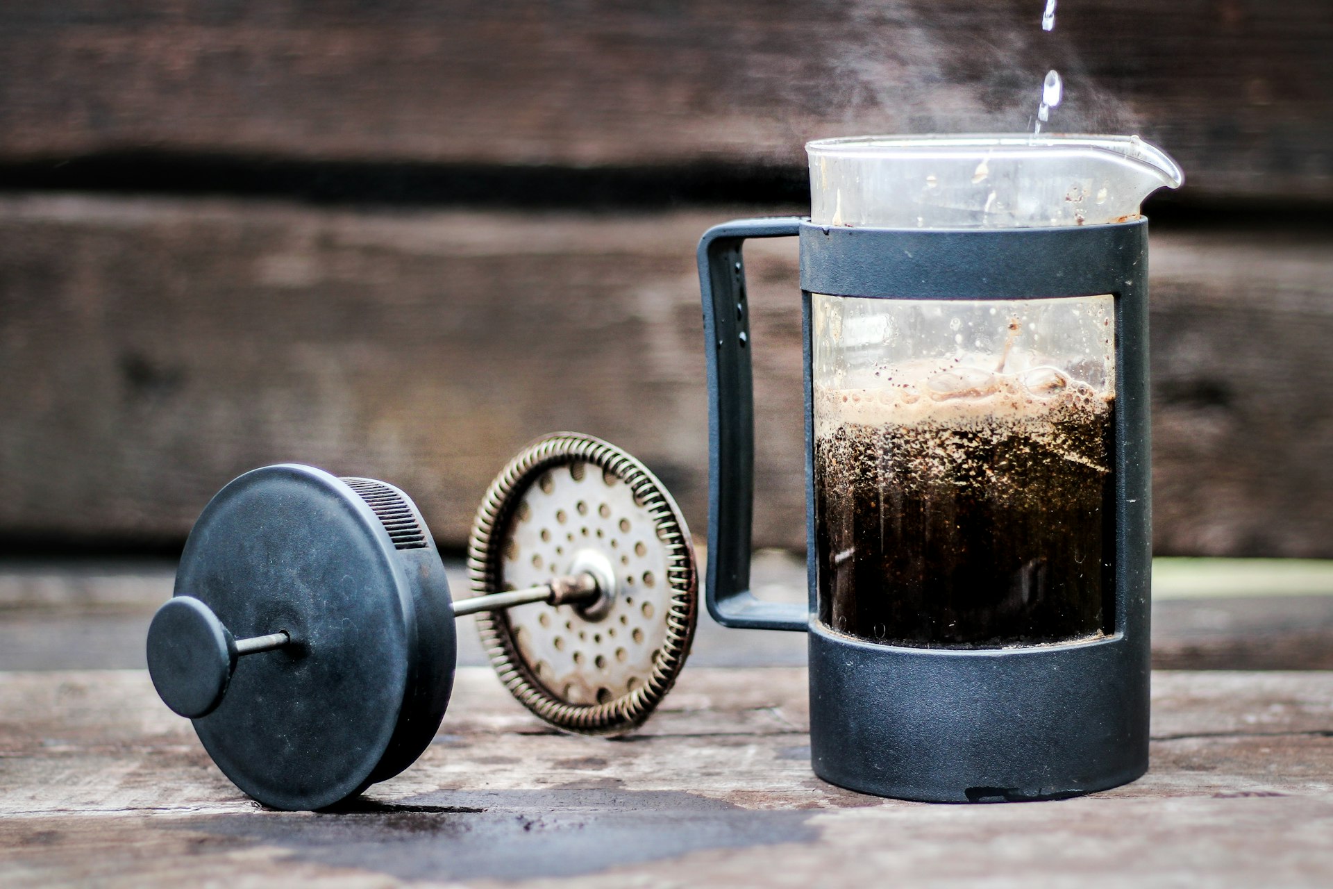 A French press filled with hot water and ground coffee, illustrating the immersion brewing process where water temperature plays a crucial role.