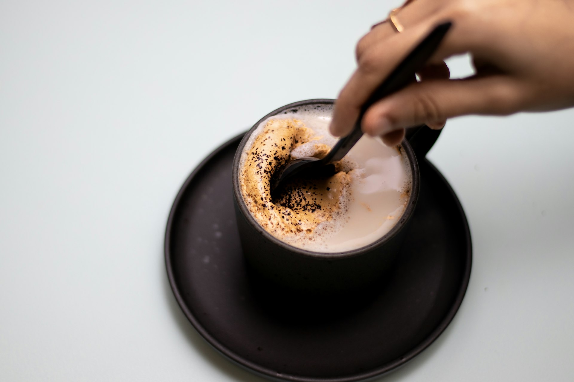 a person stirring cocoa in a cup of coffee with a spoon 