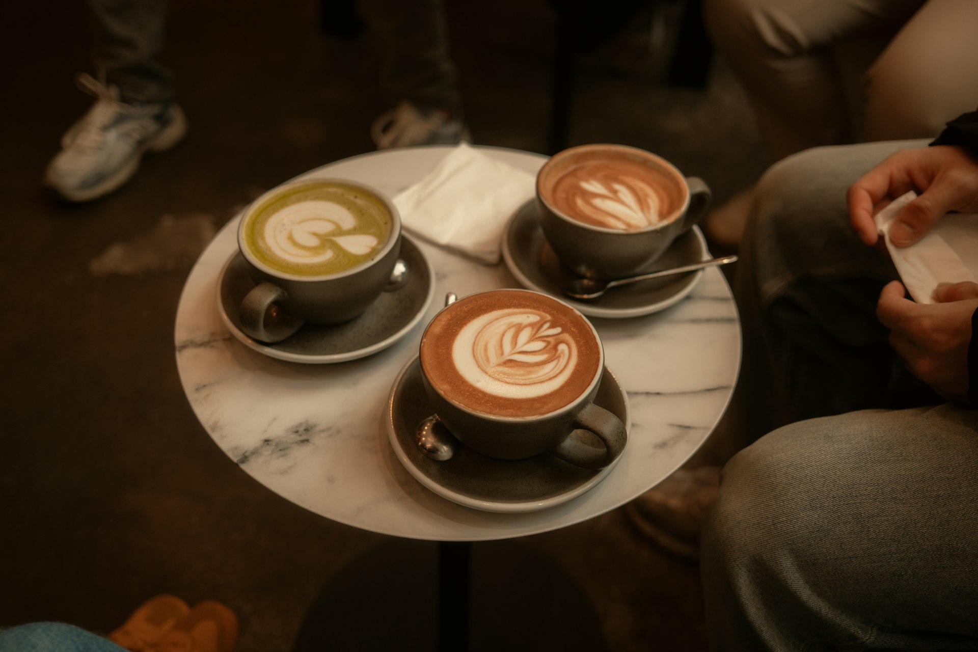 Three lattes sit on a table with a decorative design.