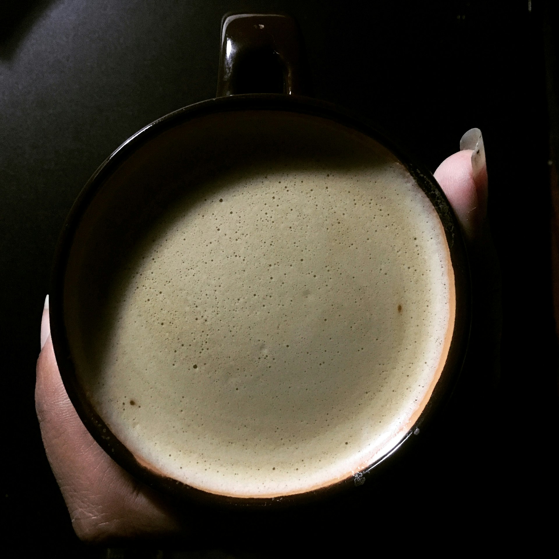a hand holding a cup of Mushroom coffee