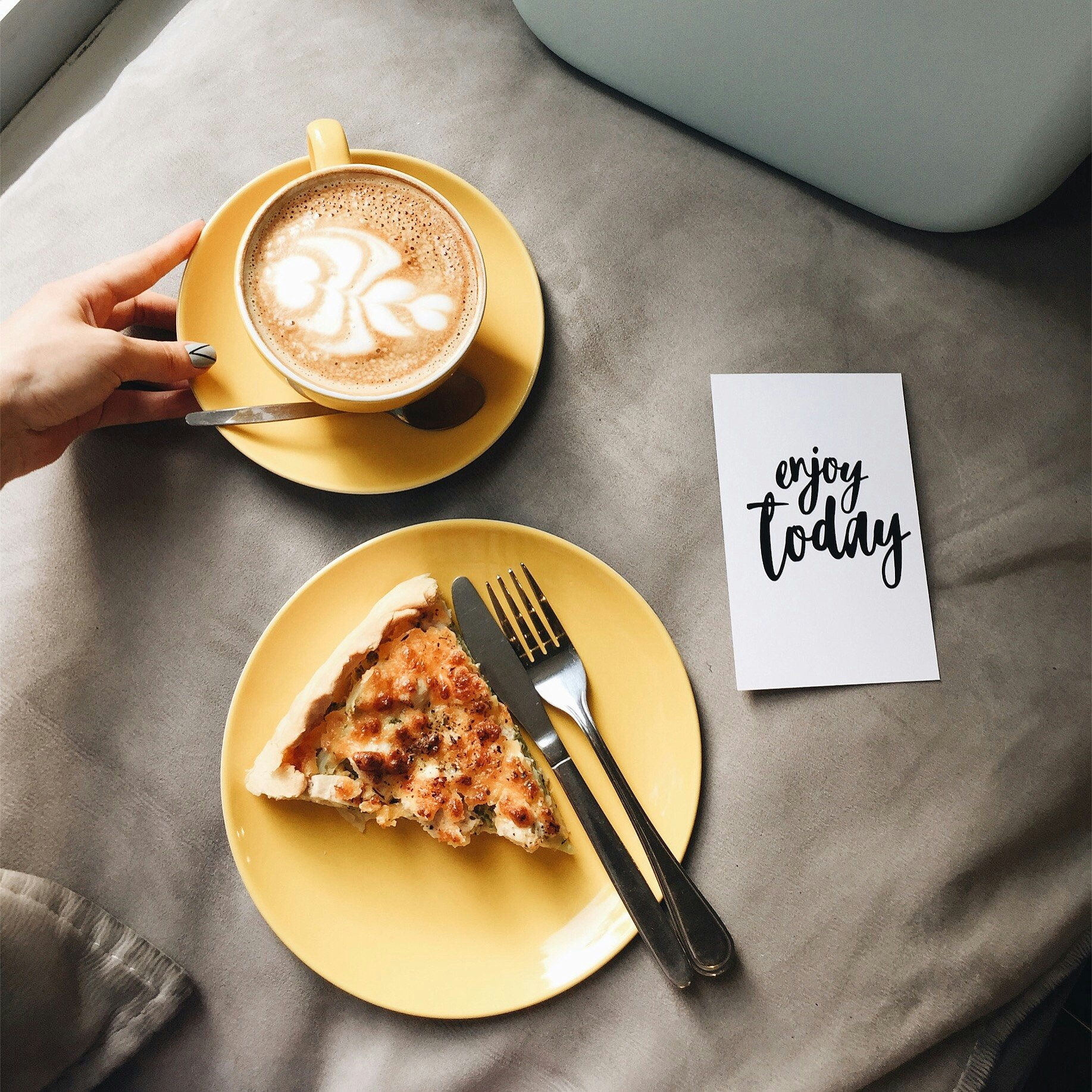  A steaming cup of coffee with a handwritten note saying "Enjoy coffee!" alongside a slice of pizza, debunking the myth that coffee stunts growth.