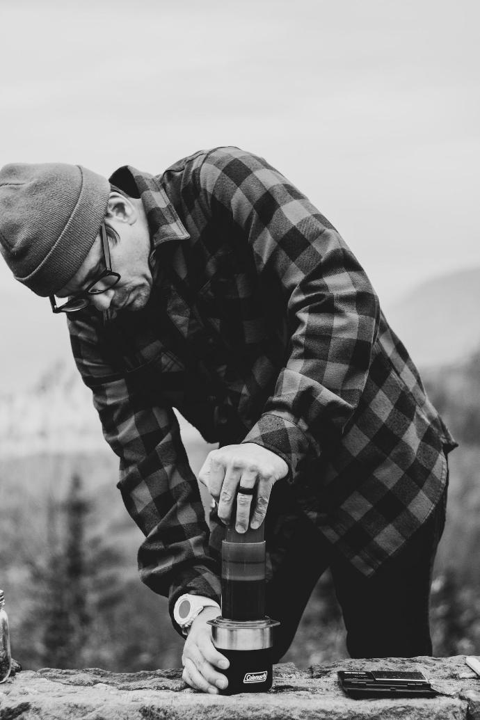 grayscale photo of man hand pressing Aeropress coffee machine to brew his coffee