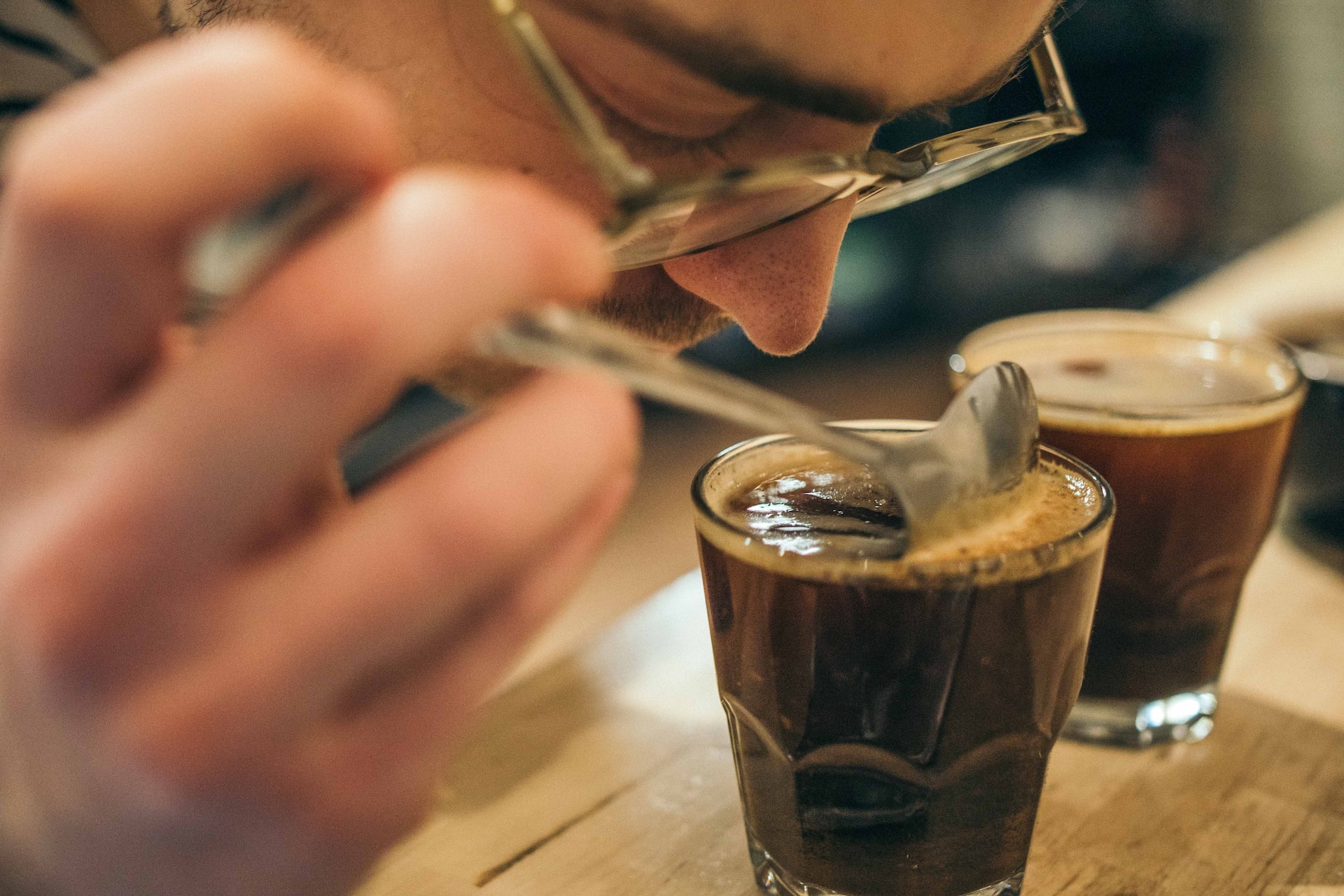 A shot of coffee enthusiasts engaged in the coffee cupping process, emphasizing the tasting technique