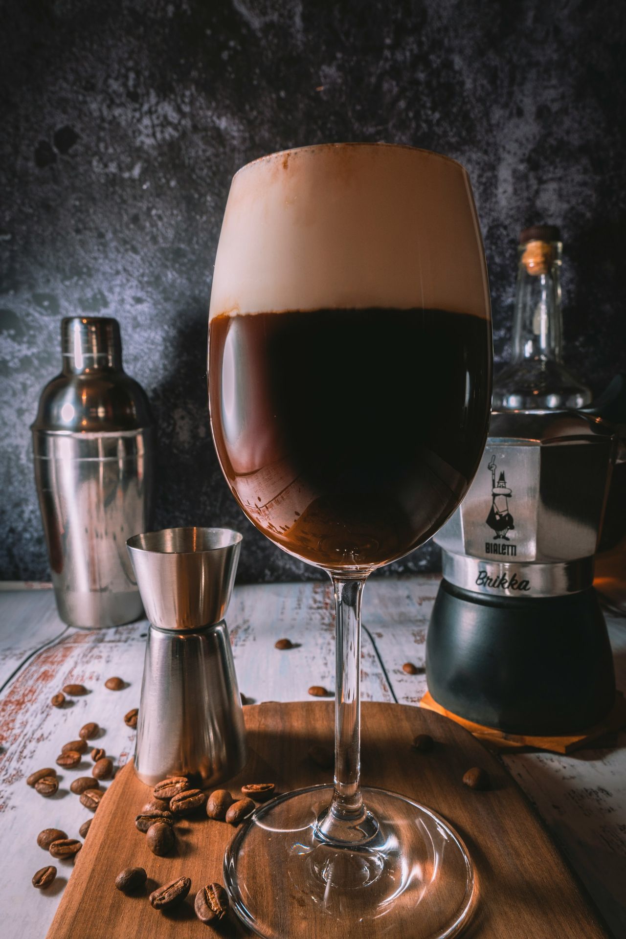A warm Irish coffee in a clear wine glass, layered with hot brewed coffee and Irish whiskey, topped with a thick layer of whipped cream.