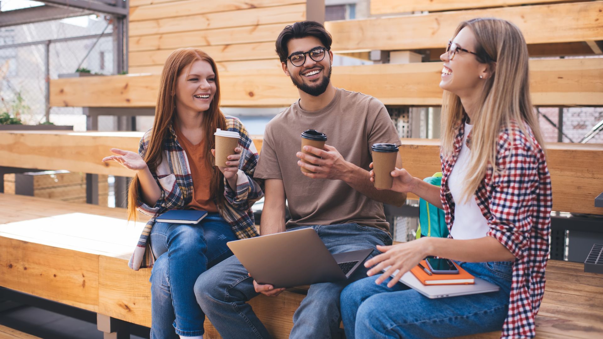 A photo showing a group of younger coffee drinkers enjoying their preferred specialty coffee while sitting on school compound benches during break time.