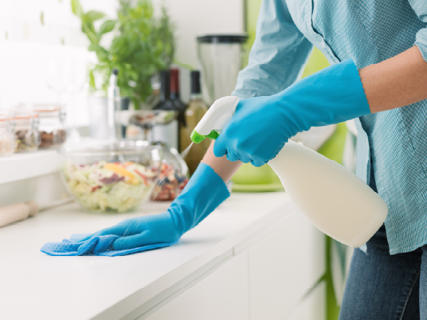 An image of a woman cleaning a surface with used coffee ground mixed with water in a bottle