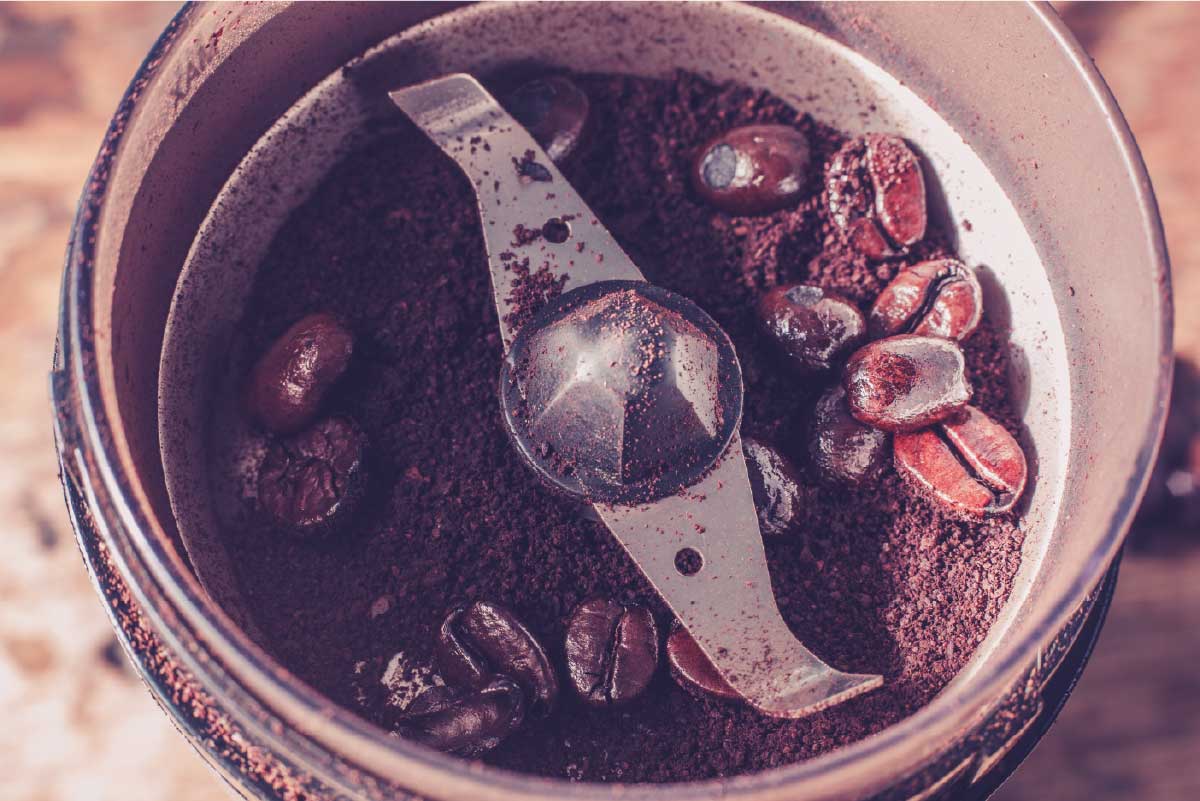 An image shows a blade coffee grinder in the process of grinding roasted coffee beans.