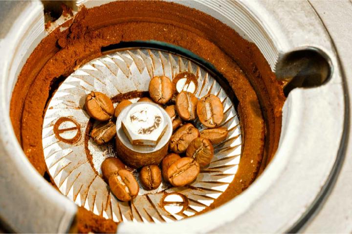 An image shows a burr coffee grinder inside with roasted coffee beans ready to grind.
