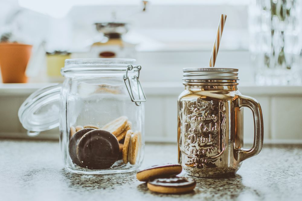 DIY coffee gift kit displaying a glass jar of homemade coffee cookies and a mason jar filled with their personalized coffee blend.