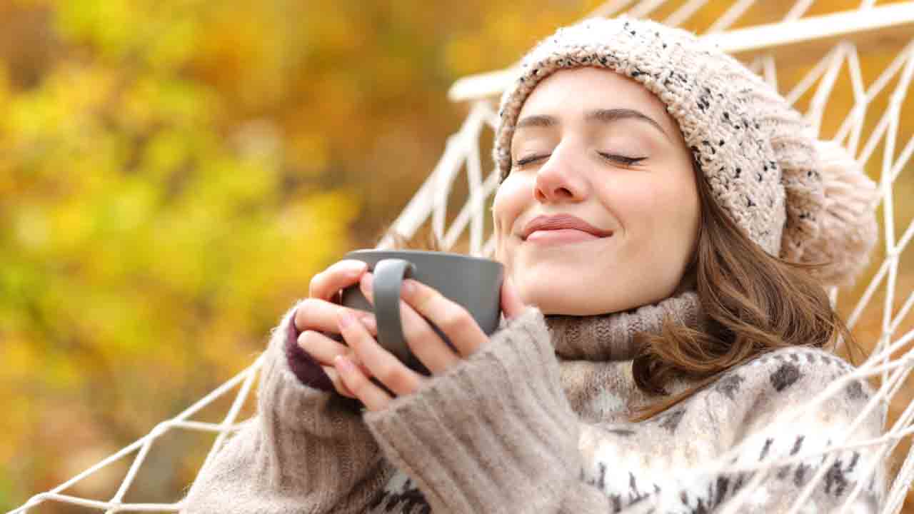 An image of a woman, eyes closed with a serene expression, inhaling the aroma of her morning coffee. The steam rises from the cup, hinting at the freshly brewed single-origin coffee beans.