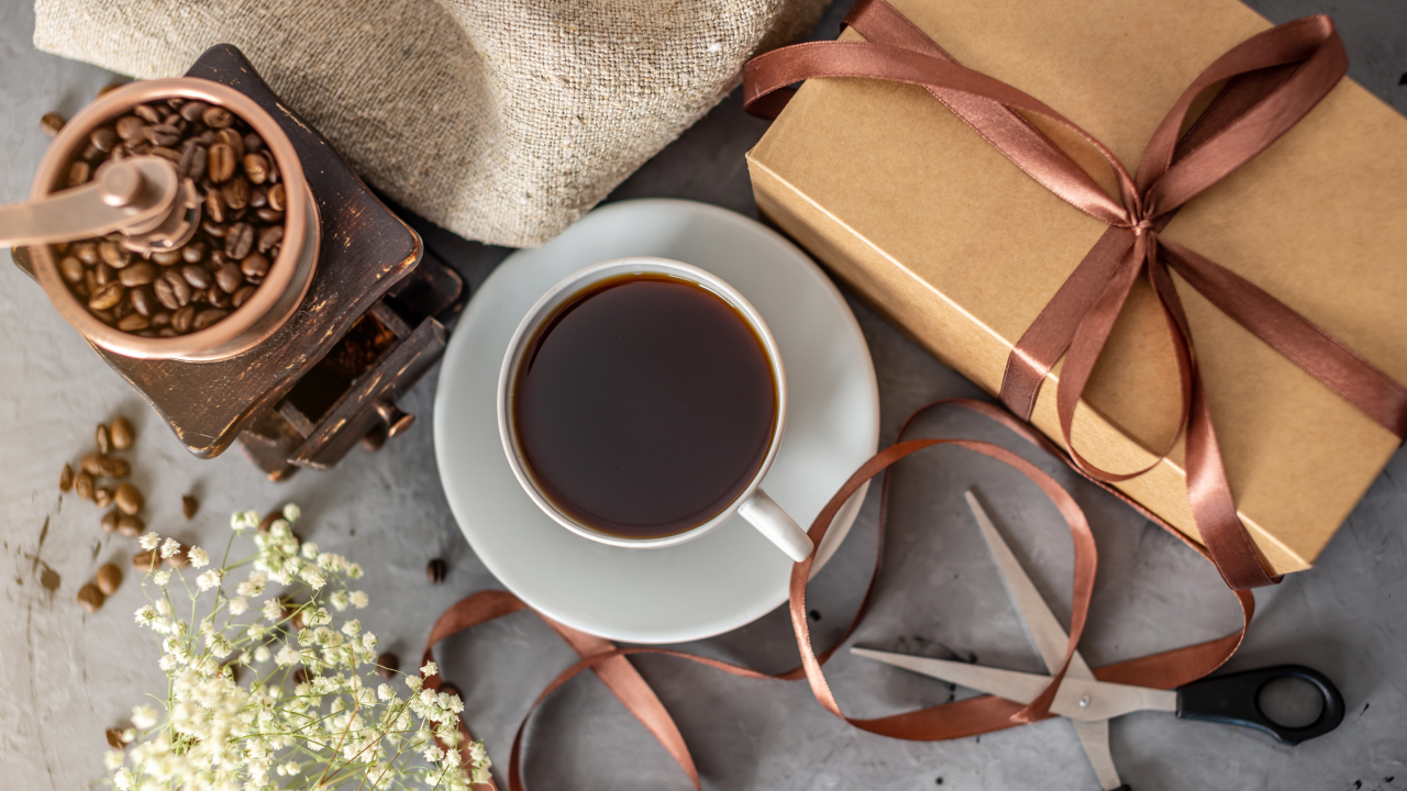 A brown gift box containing gourmet coffee beans, a stylish coffee mug, and a specialty coffee accessory, perfect for Valentine's Day