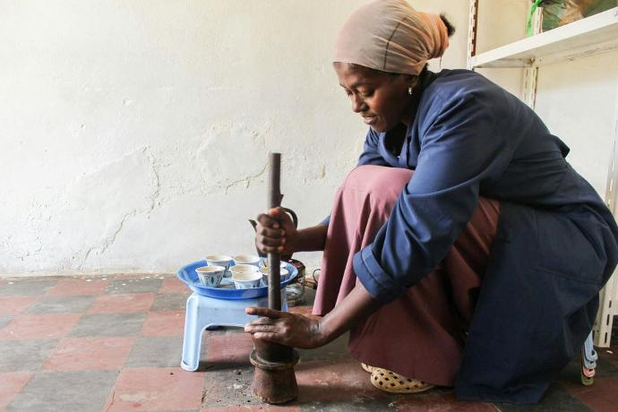 Second coffee wave: Ethiopian woman using traditional pounding method to grind coffee.