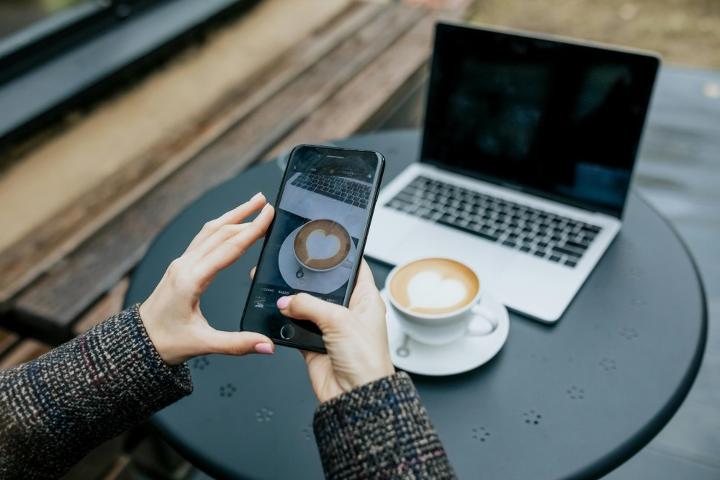 A Gen Z individual taking a photo of their coffee brew, a popular trend among younger coffee drinkers before enjoying their drink