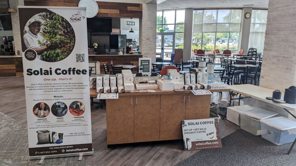 A coffee stand inside a building at a local church market day, displaying a variety of Solai Coffee products.