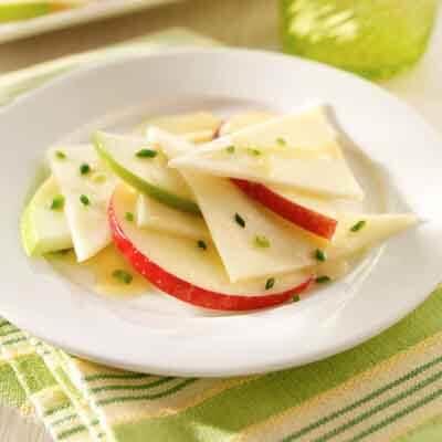 Cheese and apple slices on a plate A photo showing a white plate with apple and cheese slices.