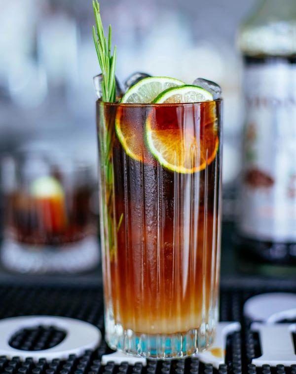 Glass of lemonade coffee filled with ice cubes, garnished with lemon slices and fresh mint leaves, perfect for hot summer days.