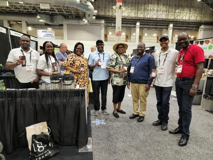 The Solai Coffee team stands proudly, smiling, holding the Solai coffee specialty pack at the Chicago Coffee Fest, exuding enthusiasm and passion for their craft.