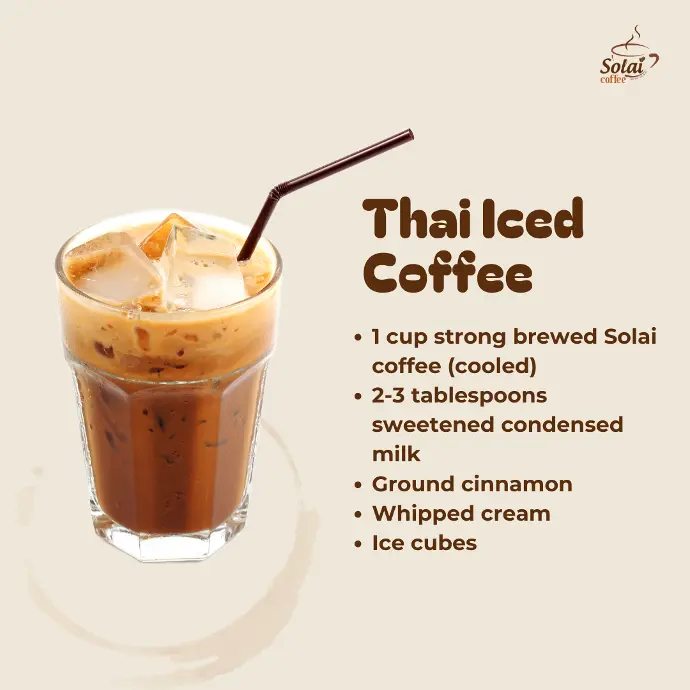 Thai Iced Coffee A clear glass filled with iced coffee swirled with creamy condensed milk, topped with whipped cream, a sprinkle of cinnamon, iced cubes, and a straw.