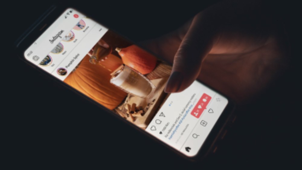  A phone screen showing someone posting a photo of their pumpkin spice latte on Instagram. 