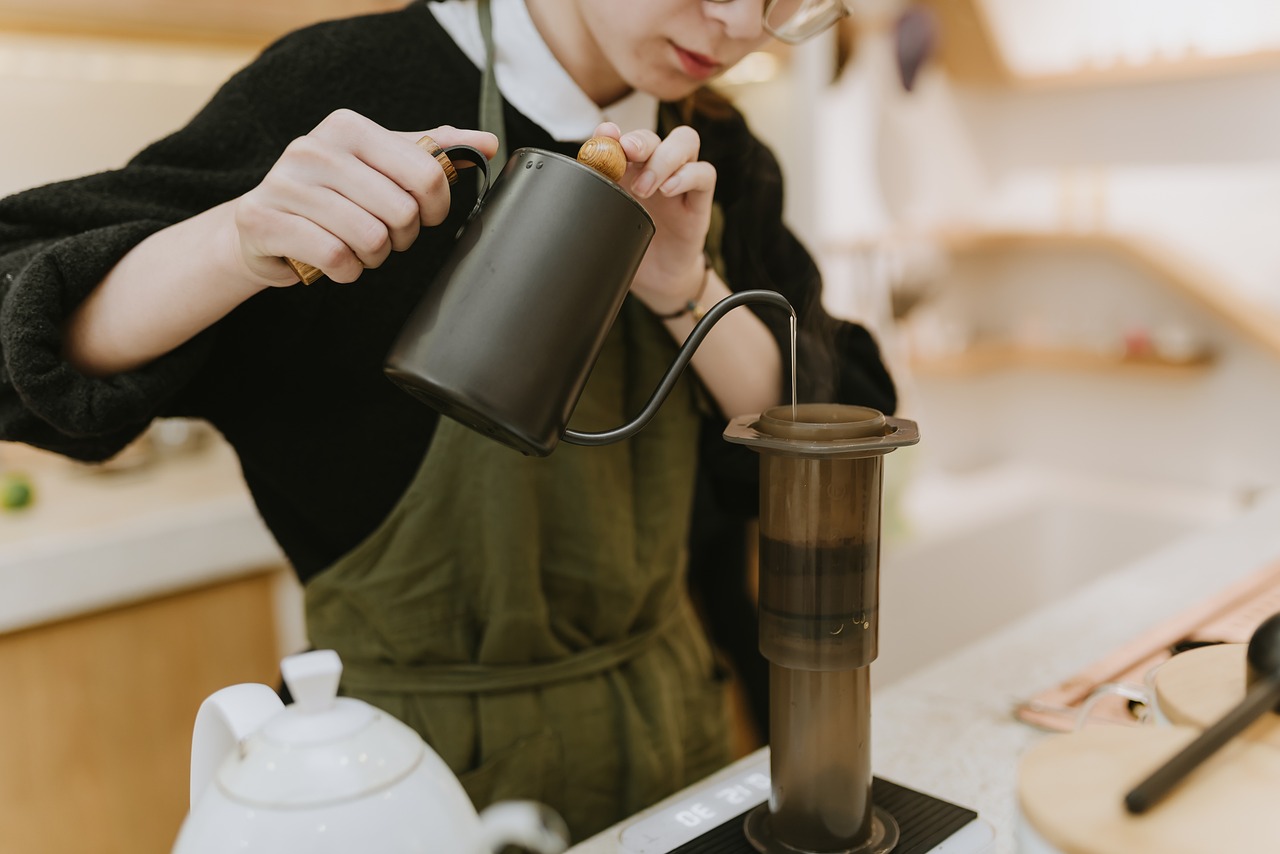 Barista carefully pouring filtered water into an AeroPress for brewing coffee, ensuring precise extraction.