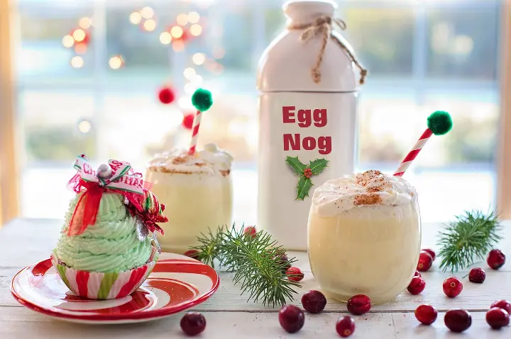 A creamy eggnog frappuccino topped with whipped cream and a dash of nutmeg served in a clear cup with a festive holiday garnish.