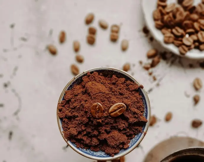 A close-up of finely ground coffee with roasted coffee beans on a portafilter, highlighting the texture and richness of the grind.