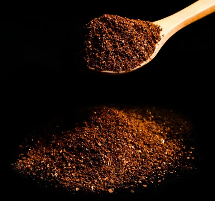 a spoon filled with coarsely ground coffee beans showcases the contrast in grind sizes. 