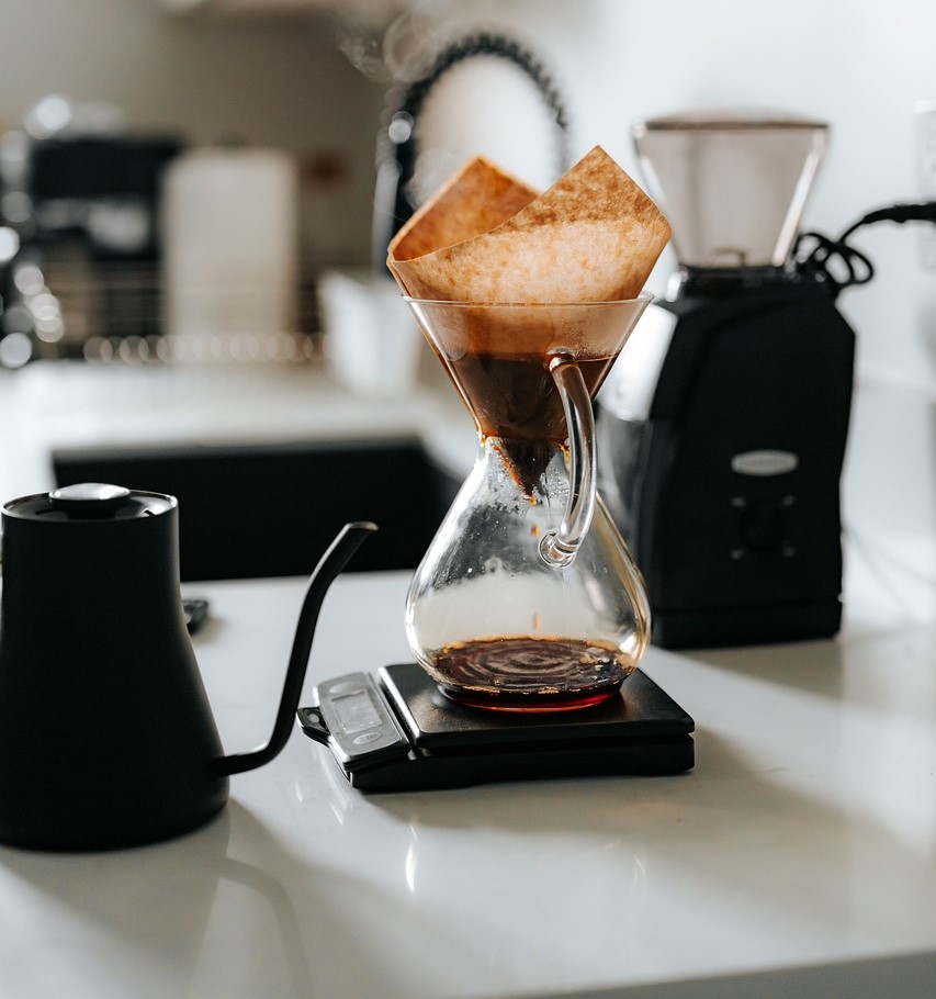 This image showcases a home coffee brewing setup with a Chemex pour-over coffee maker placed on a digital scale. 