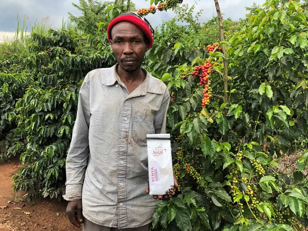 A picture of a Kenyan coffee farmer holding a pack of coffee beans symbolizes the direct trade relationship and fair wages.