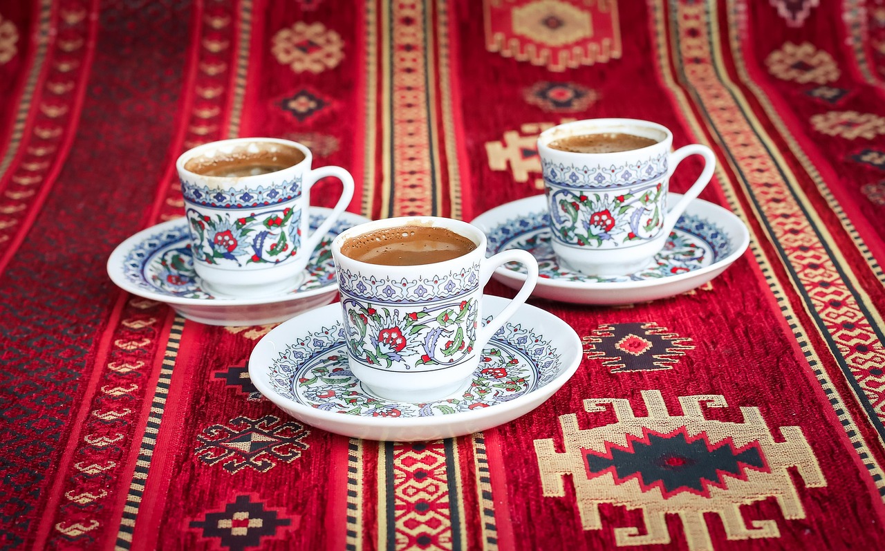 Moroccan Pepper Coffee is served in beautifully decorated white and blue ceramic cups, elegantly placed on a red carpet, evoking the rich cultural tradition of Moroccan coffee rituals.