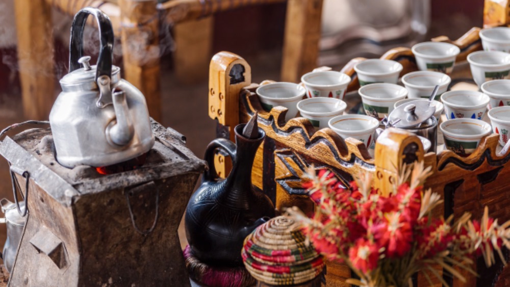 A traditional Ethiopian coffee ceremony is set up with a clay pot on site, filled with freshly brewed Buna coffee, ready for serving in small cups, symbolizing cultural heritage.