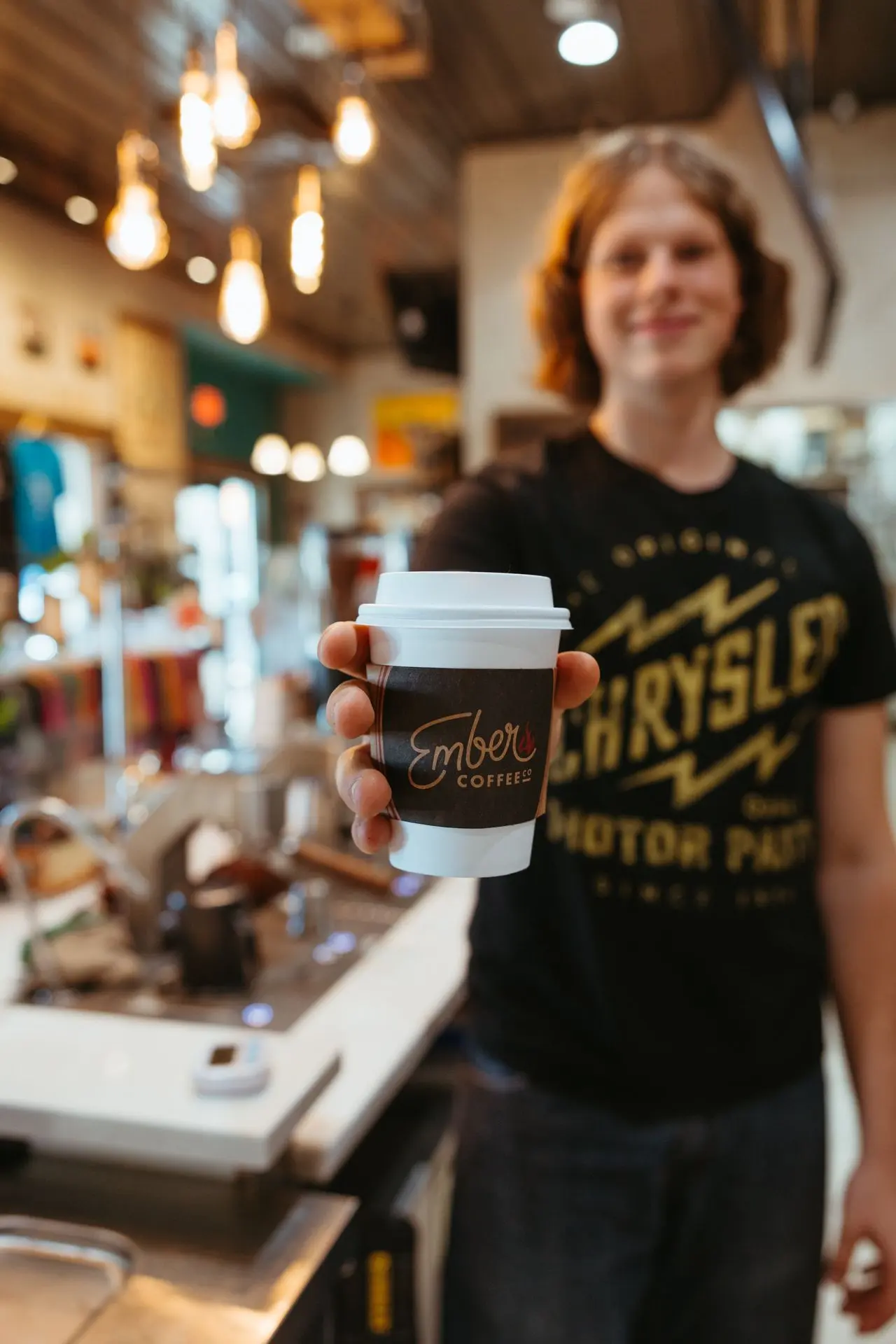 A barista showcasing a cup of latte from ember coffee 