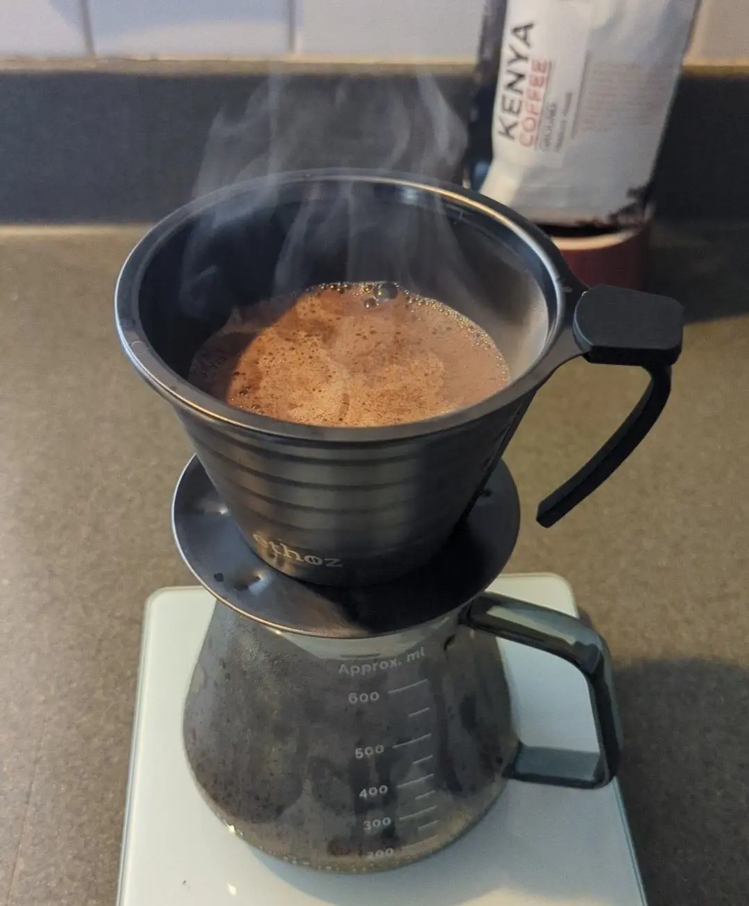 A person carefully making pour-over coffee with freshly ground Kenyan beans, water flowing in a slow circular motion.