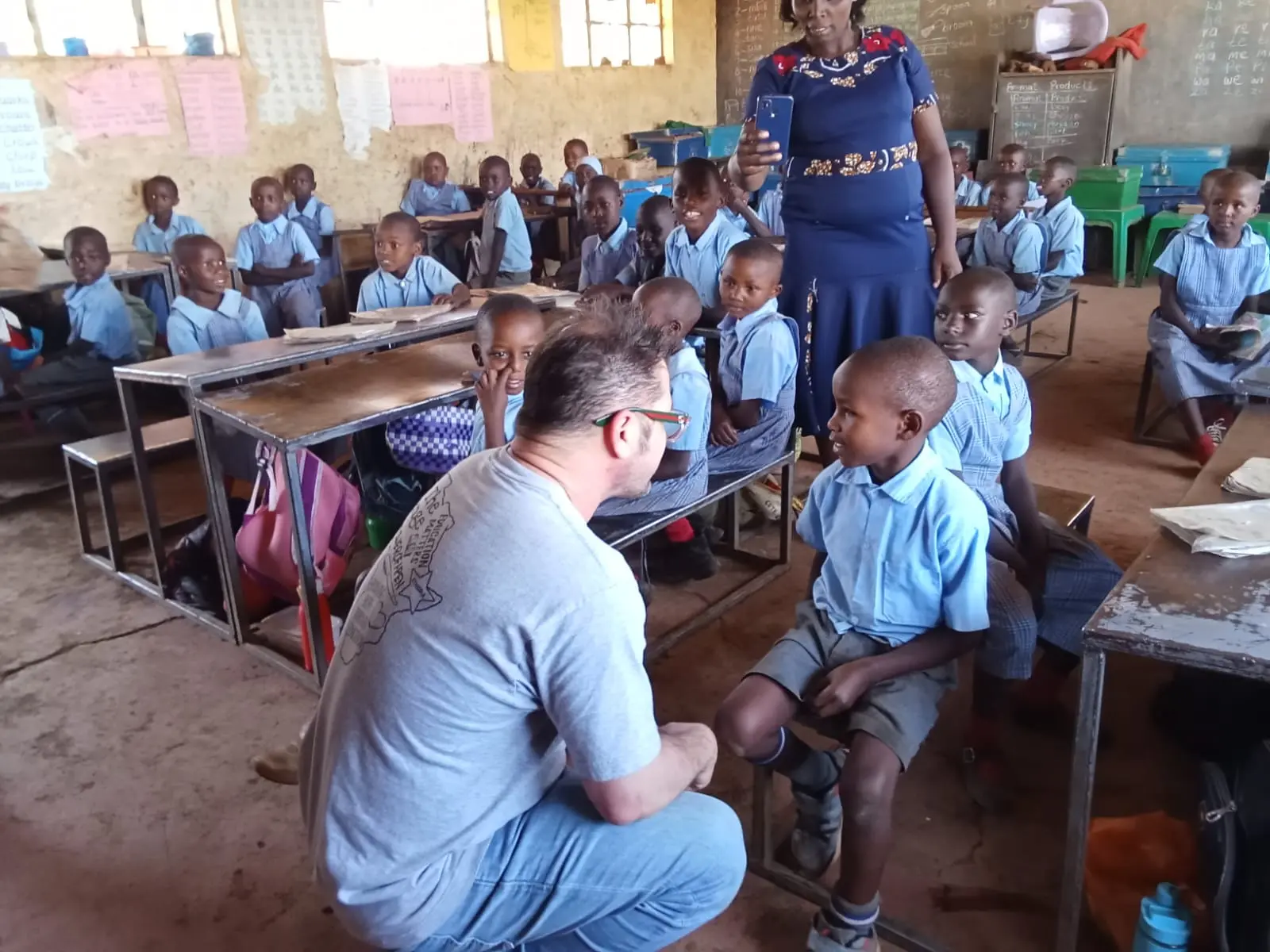 Brad from Acts of Wisdom interacts one-on-one with elementary school children at Nyakinyua Primary, listening to their stories and sharing words of encouragement.