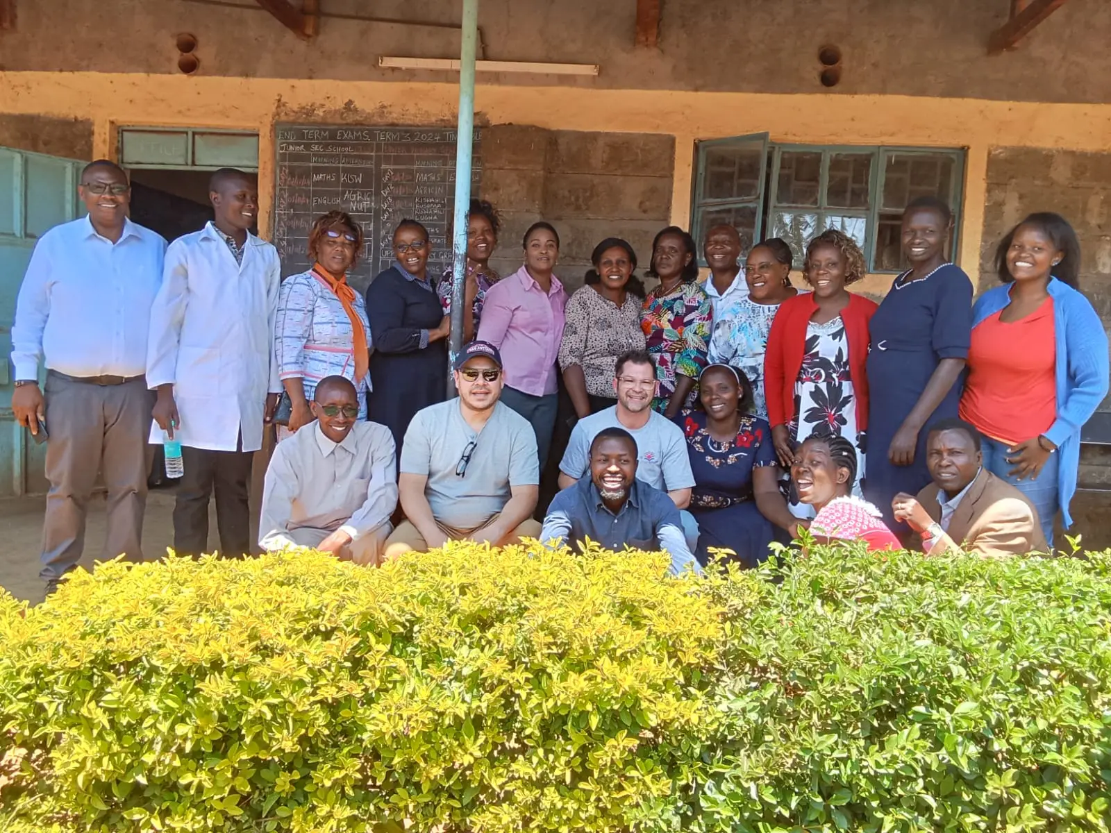 Brad Otto and Marvin Tejada from Acts of Wisdom pose for a photo with the Solai Coffee team, Liwani Estate owner Stephen Kuria, and Nyakinyua Primary School teachers on the school grounds, marking a moment of partnership and shared purpose.