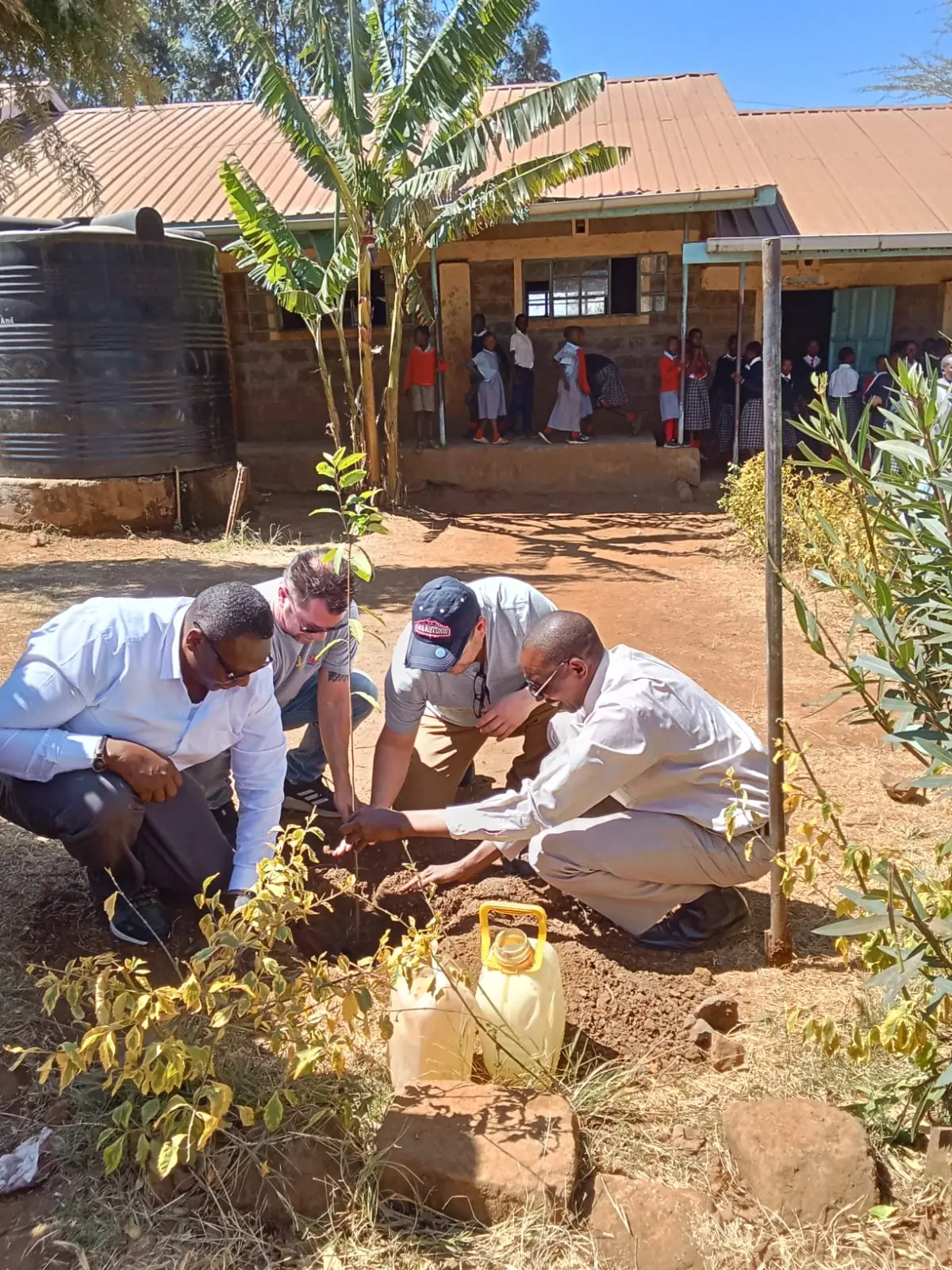 Members of Acts of Wisdom and the Solai Coffee team plant a tree together at Nyakinyua Primary School, symbolizing growth, unity, and the long-term partnership between both organizations.